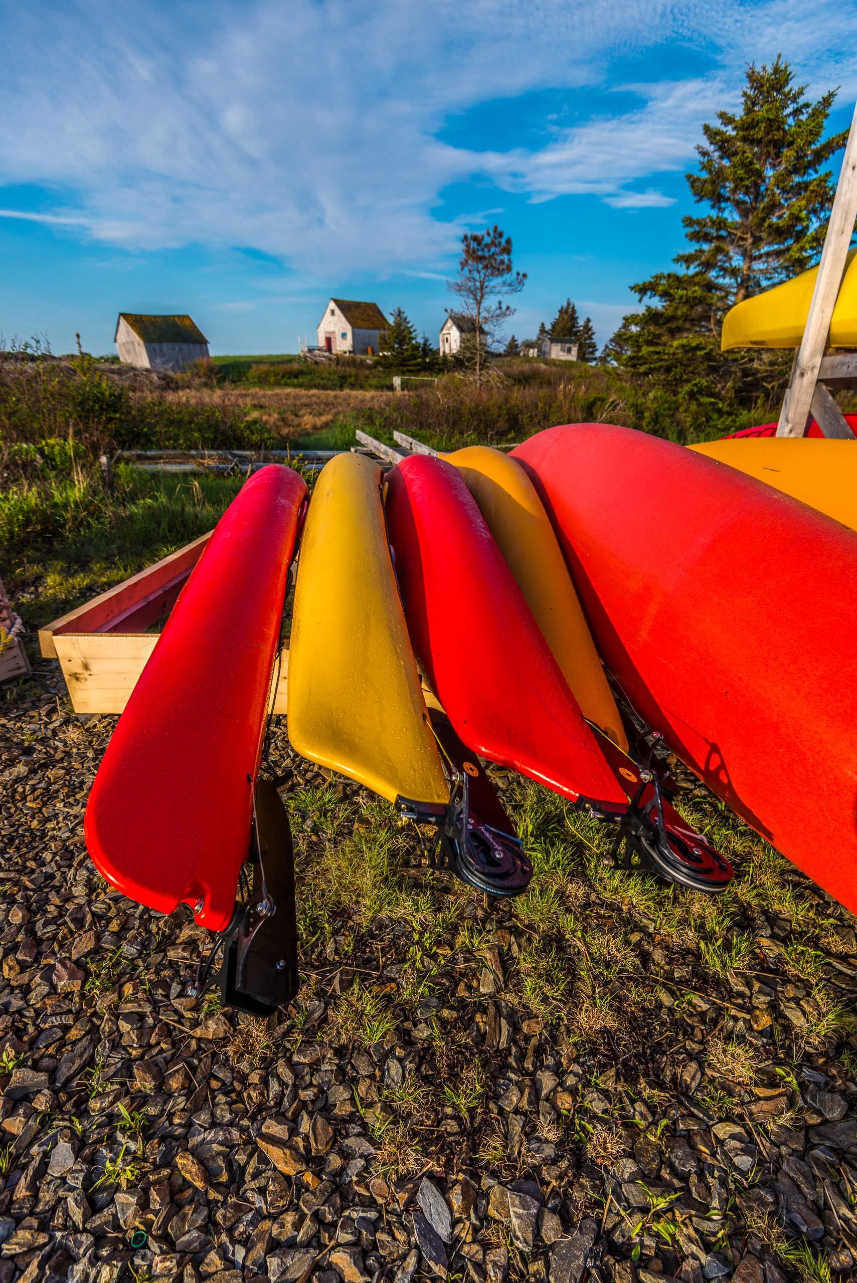 Six brightly coloured kayaks lined up on a wood base